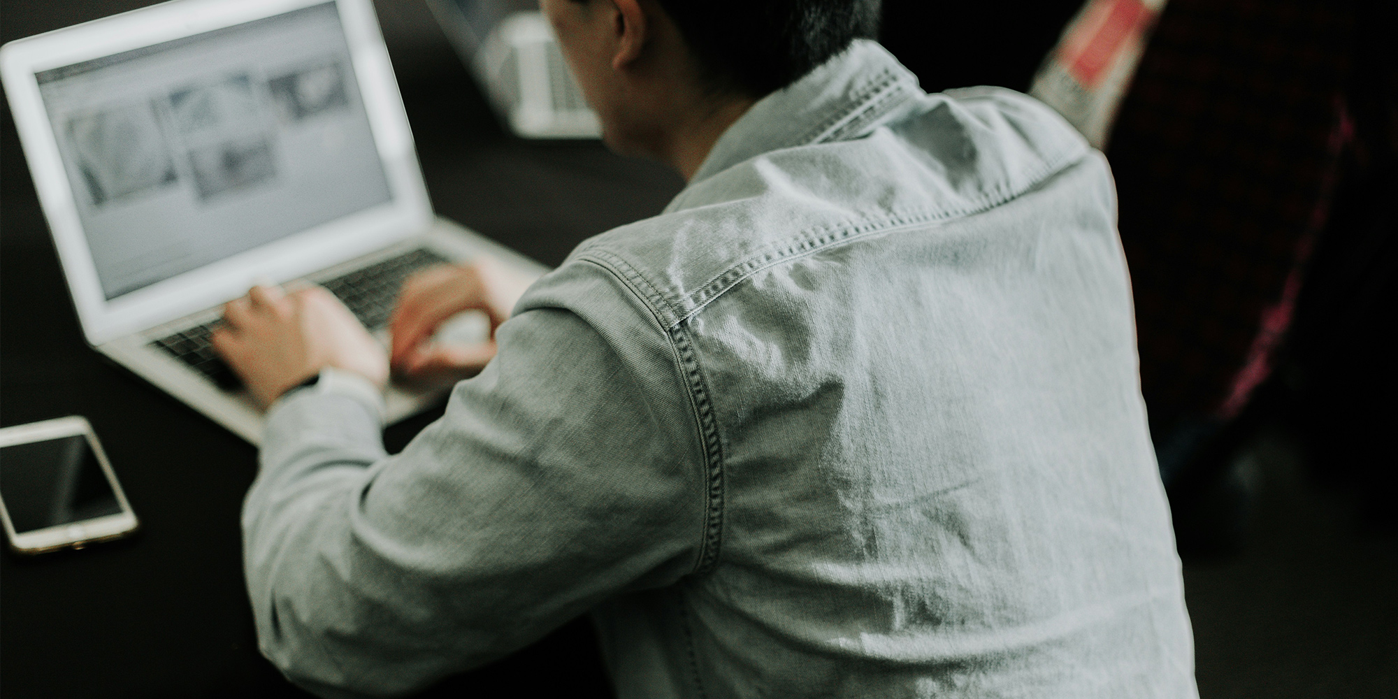A man wearing a shirt working at a laptop