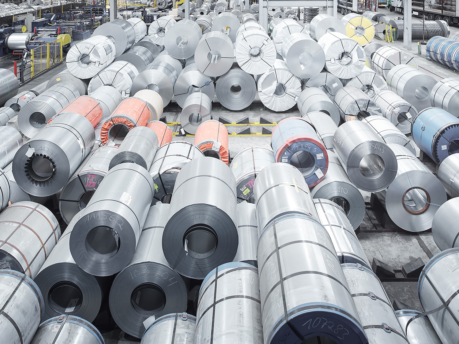 OKS_Landscape_04 Stacks of coiled steel rolls in various sizes and finishes organized in a steel service center, showcasing the variety of steel products available for industrial use.