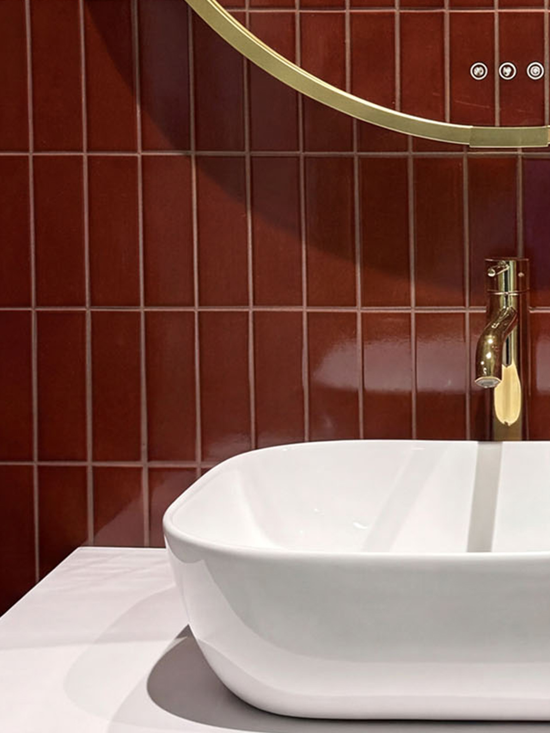Kakelspecialisten_content_05 Dunkelrote Fliesen vor einem weißen Waschtisch mit goldenem Wasserhahn